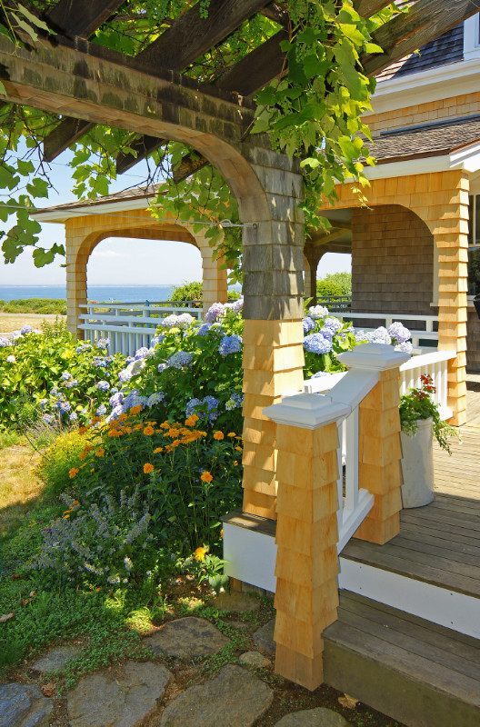 Cette photo montre un porche d'entrée de maison avant chic de taille moyenne avec une terrasse en bois et une pergola.