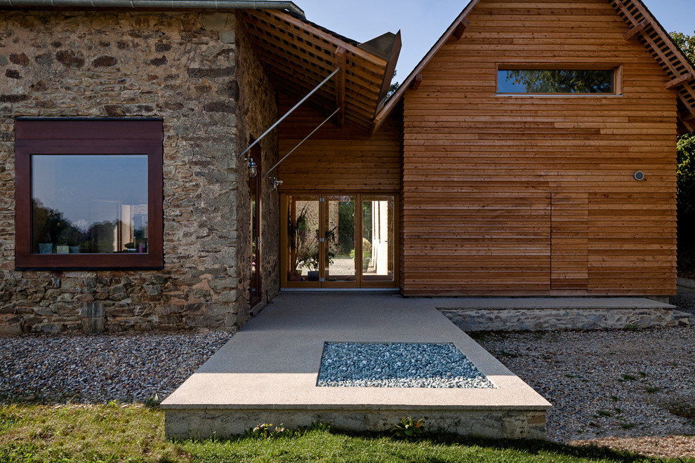 Réalisation d'un porche d'entrée de maison arrière champêtre de taille moyenne avec du béton estampé et une extension de toiture.