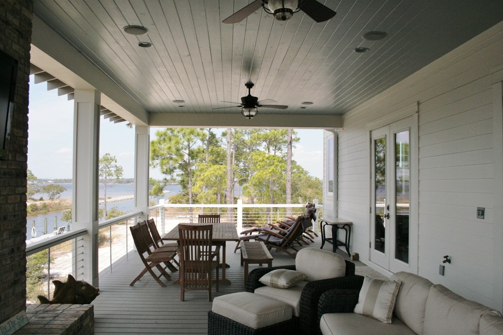 Exemple d'un porche d'entrée de maison arrière bord de mer avec une terrasse en bois et une extension de toiture.