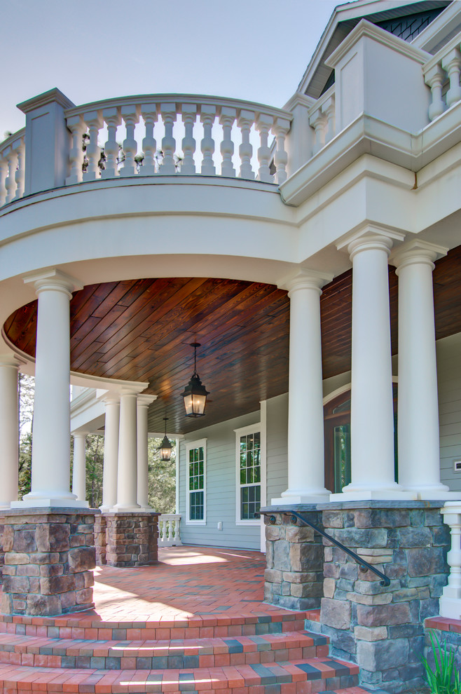 Diseño de terraza clásica grande en patio delantero y anexo de casas con adoquines de ladrillo