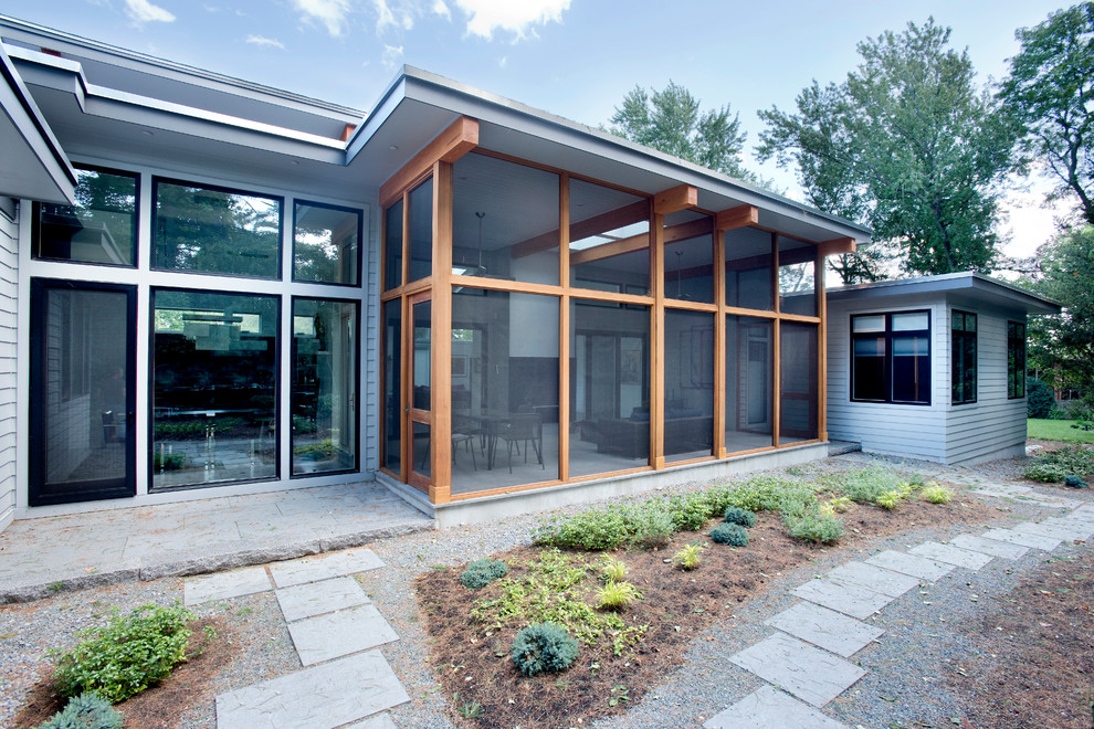 Aménagement d'un grand porche d'entrée de maison arrière moderne avec une moustiquaire, du carrelage et une extension de toiture.