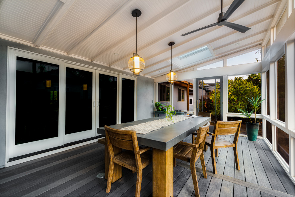 Exemple d'un grand porche d'entrée de maison arrière tendance avec une moustiquaire, une terrasse en bois et une extension de toiture.