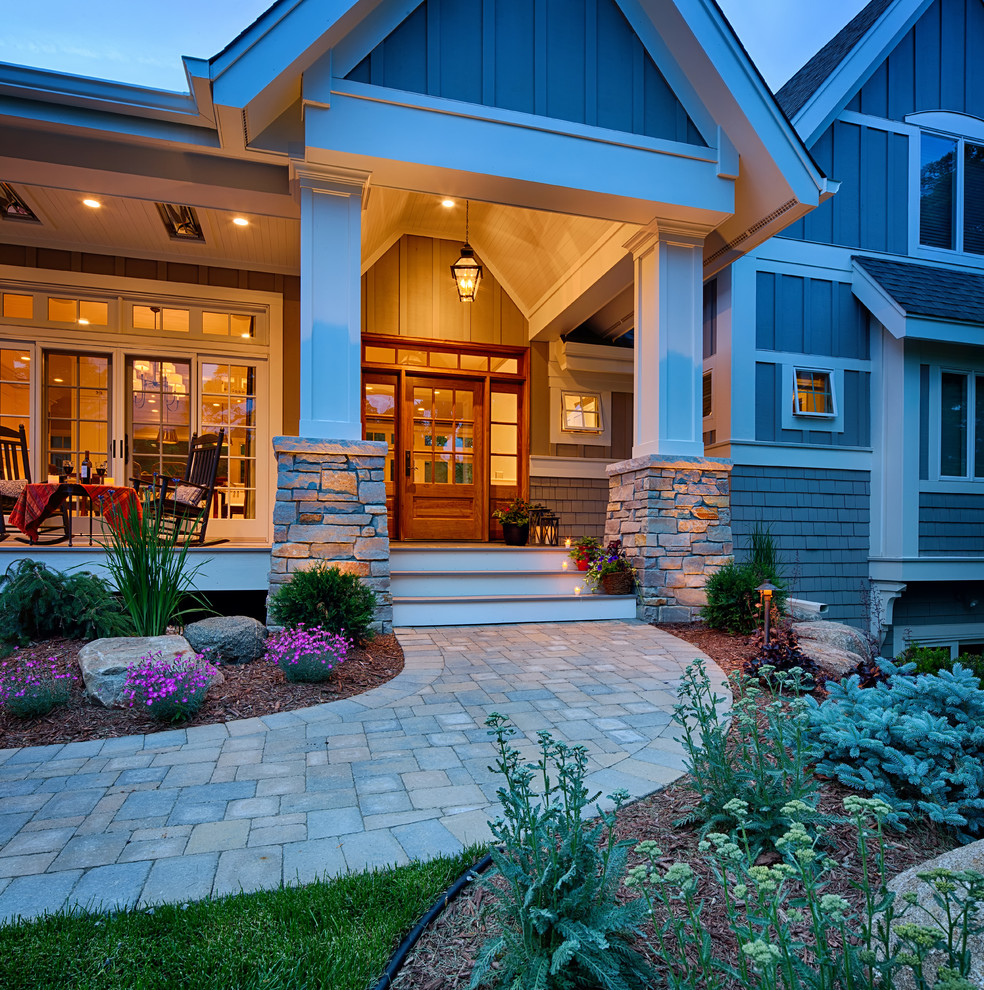 Aménagement d'un grand porche d'entrée de maison avant craftsman avec une terrasse en bois et une extension de toiture.