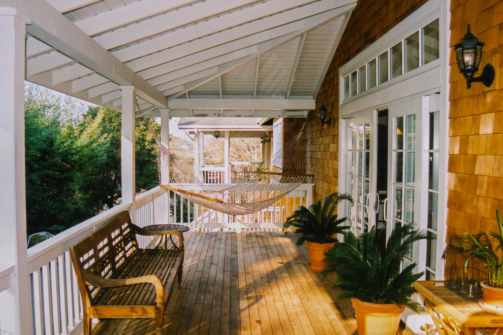 Idées déco pour un porche d'entrée de maison latéral craftsman de taille moyenne avec une terrasse en bois et une extension de toiture.