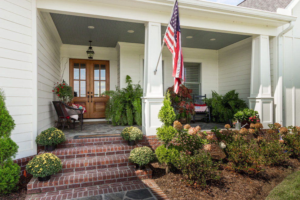 Immagine di un portico country di medie dimensioni e davanti casa con pavimentazioni in pietra naturale e un tetto a sbalzo