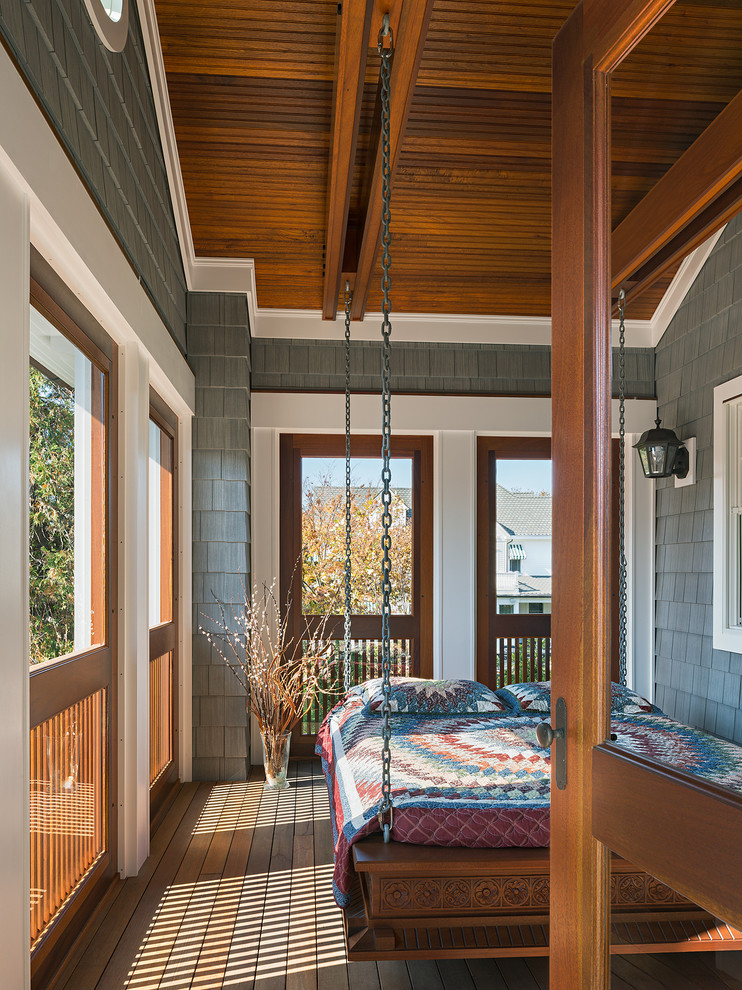 This is an example of a large traditional screened-in back porch design in New York with decking and a roof extension.