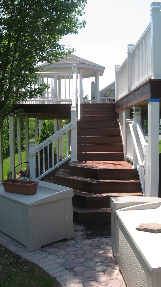This is an example of a mid-sized traditional stone back porch design in New York.