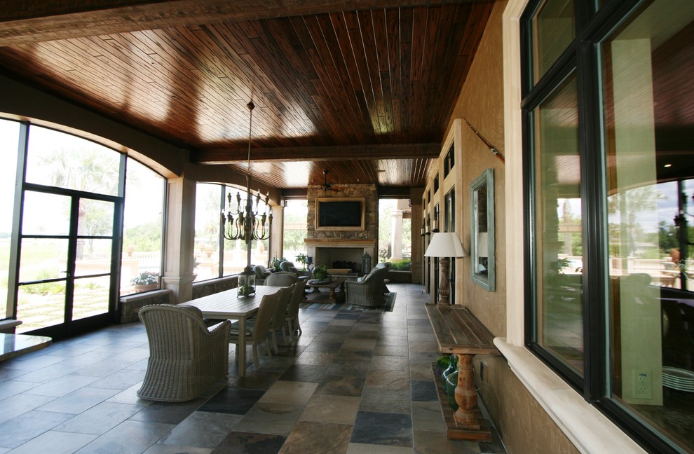 Idée de décoration pour un grand porche d'entrée de maison latéral méditerranéen avec du carrelage et une extension de toiture.