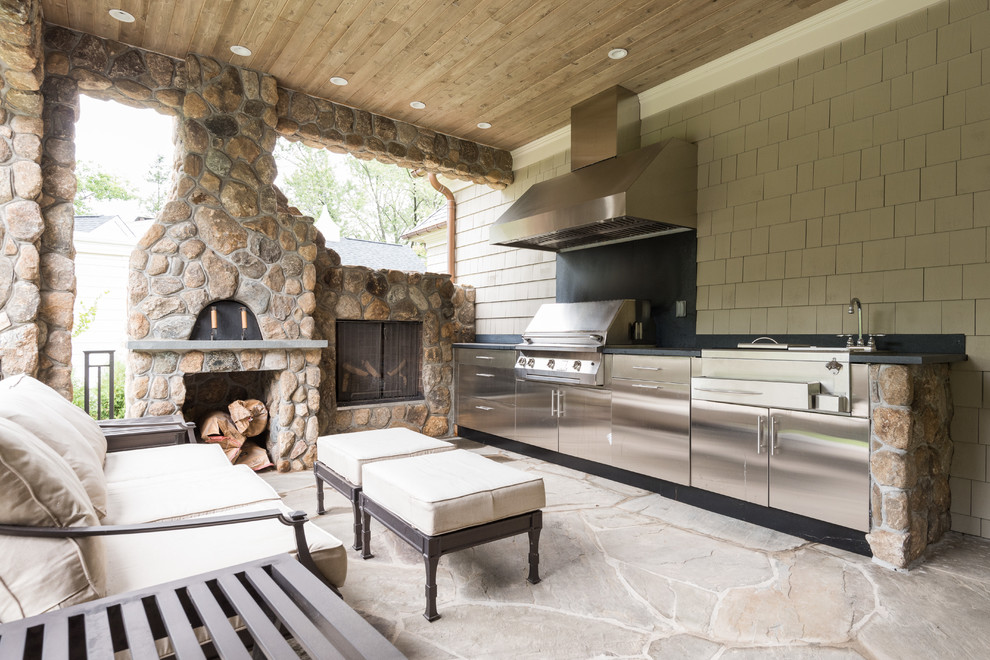 Réalisation d'un grand porche d'entrée de maison arrière tradition avec une cuisine d'été, des pavés en pierre naturelle et une extension de toiture.