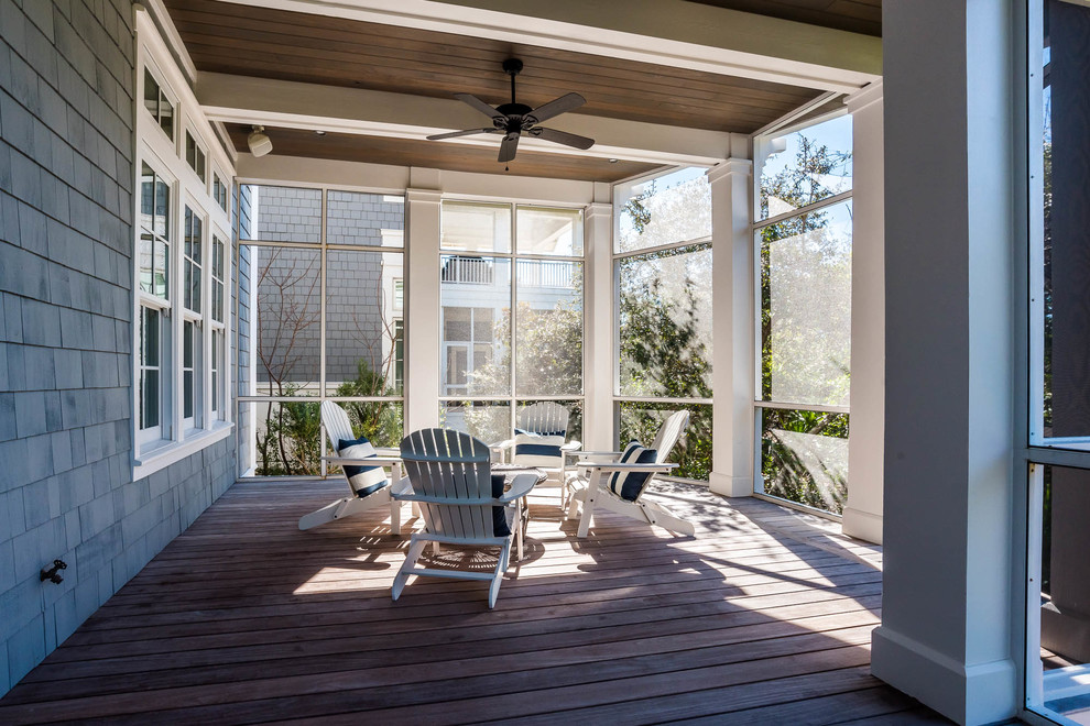 Cette photo montre un très grand porche d'entrée de maison arrière bord de mer avec une moustiquaire, une terrasse en bois et une extension de toiture.