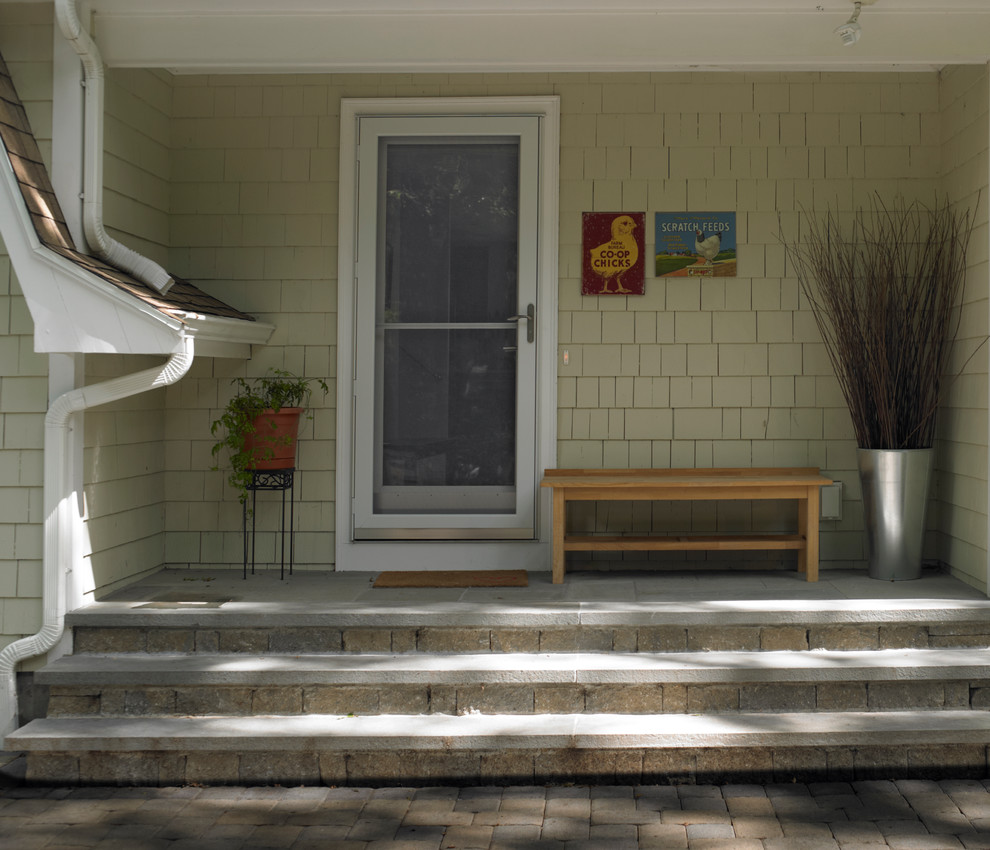 This is an example of a mid-sized traditional brick front porch design in Boston with a roof extension.