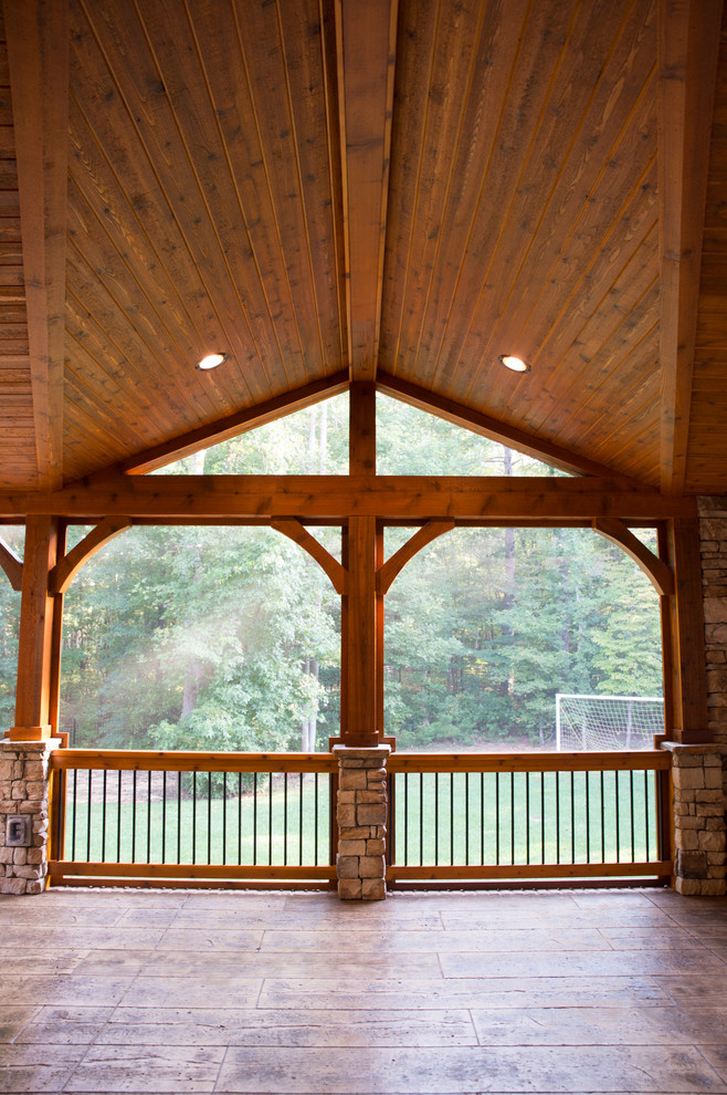 Cette photo montre un grand porche d'entrée de maison arrière montagne avec une moustiquaire, du béton estampé et une extension de toiture.
