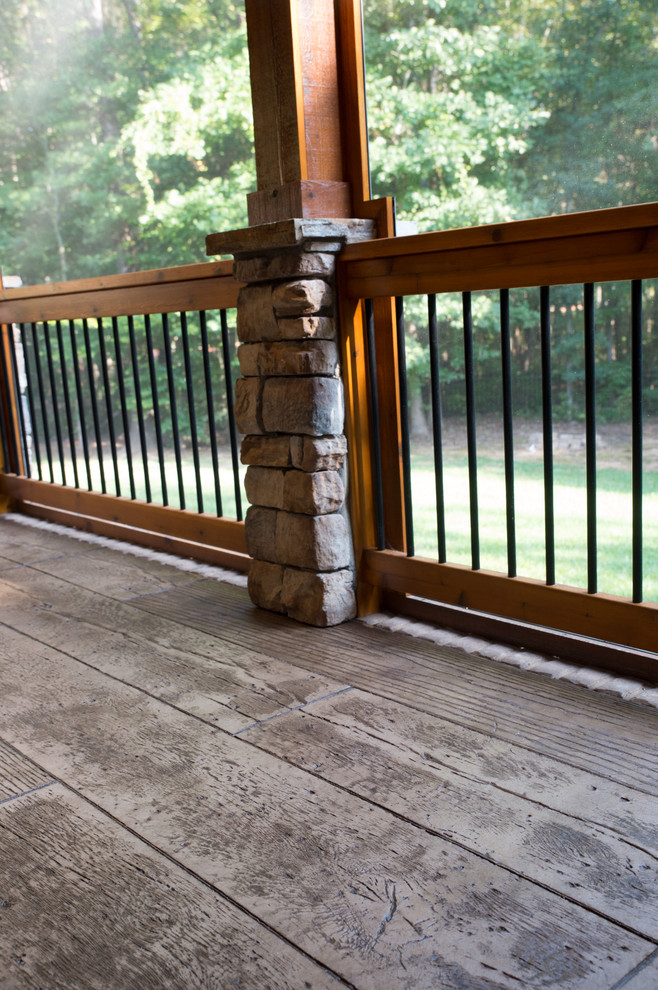 Inspiration for a large rustic back screened veranda in Charlotte with stamped concrete and a roof extension.