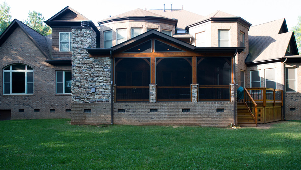Cette image montre un grand porche d'entrée de maison arrière chalet avec une moustiquaire, du béton estampé et une extension de toiture.