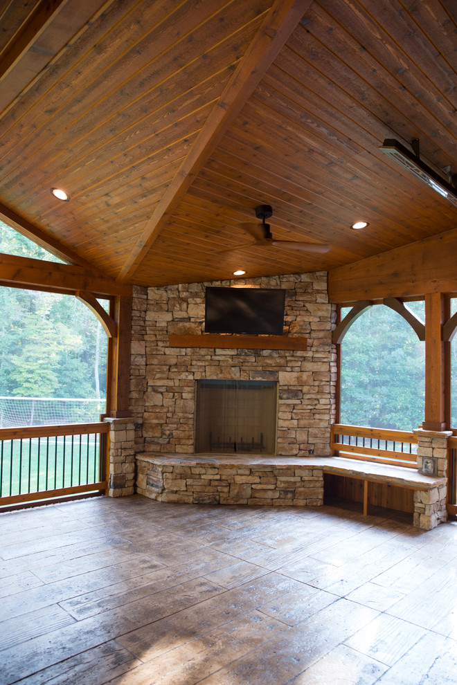 Large mountain style stamped concrete screened-in back porch idea in Charlotte with a roof extension