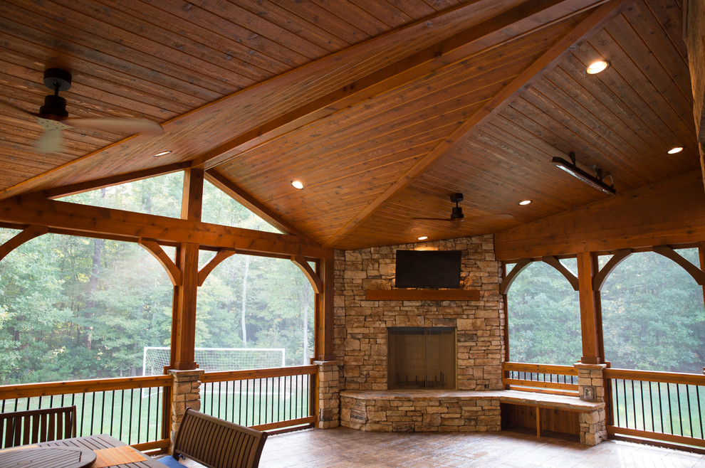 Exemple d'un grand porche d'entrée de maison arrière montagne avec une moustiquaire, du béton estampé et une extension de toiture.