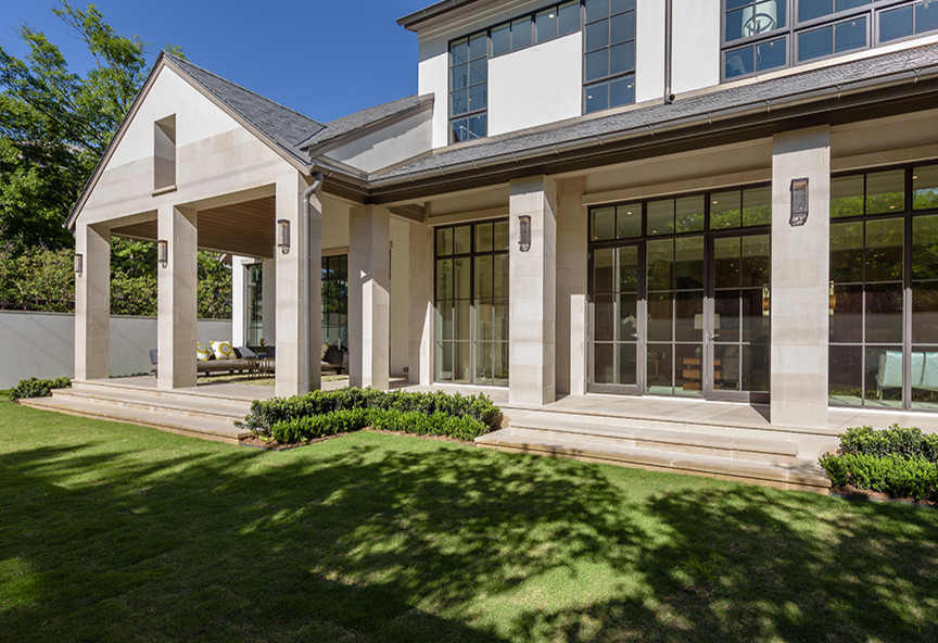 Cette photo montre un grand porche d'entrée de maison arrière chic avec des pavés en pierre naturelle et une extension de toiture.
