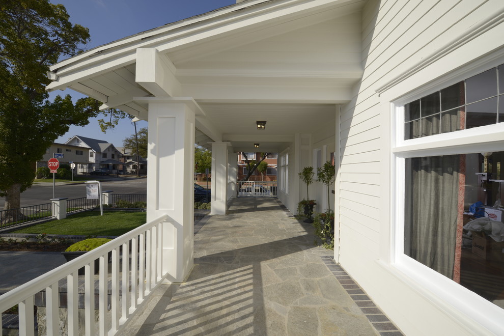 Ejemplo de terraza de estilo americano grande en patio delantero y anexo de casas con adoquines de piedra natural