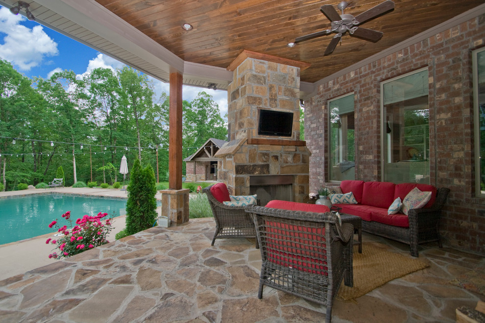 Photo of a medium sized rustic back veranda in Little Rock with natural stone paving, a roof extension and a fire feature.