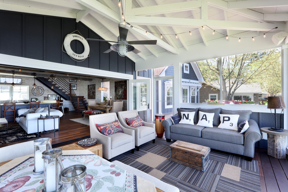 Aménagement d'un grand porche d'entrée de maison avant bord de mer avec une terrasse en bois et une extension de toiture.
