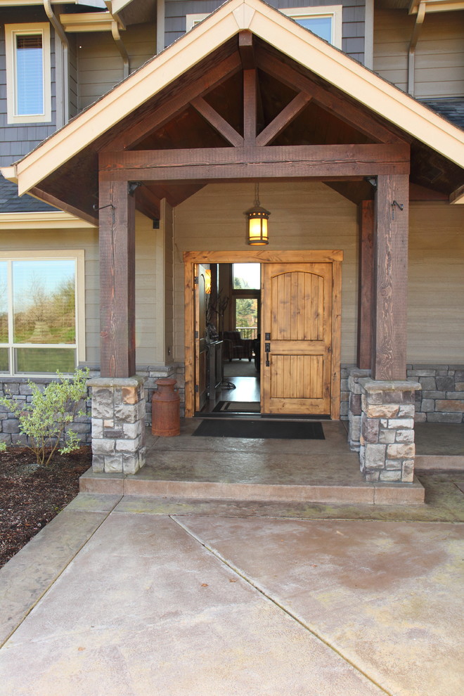 Inspiration for a large rustic stamped concrete front porch remodel in Portland with a roof extension
