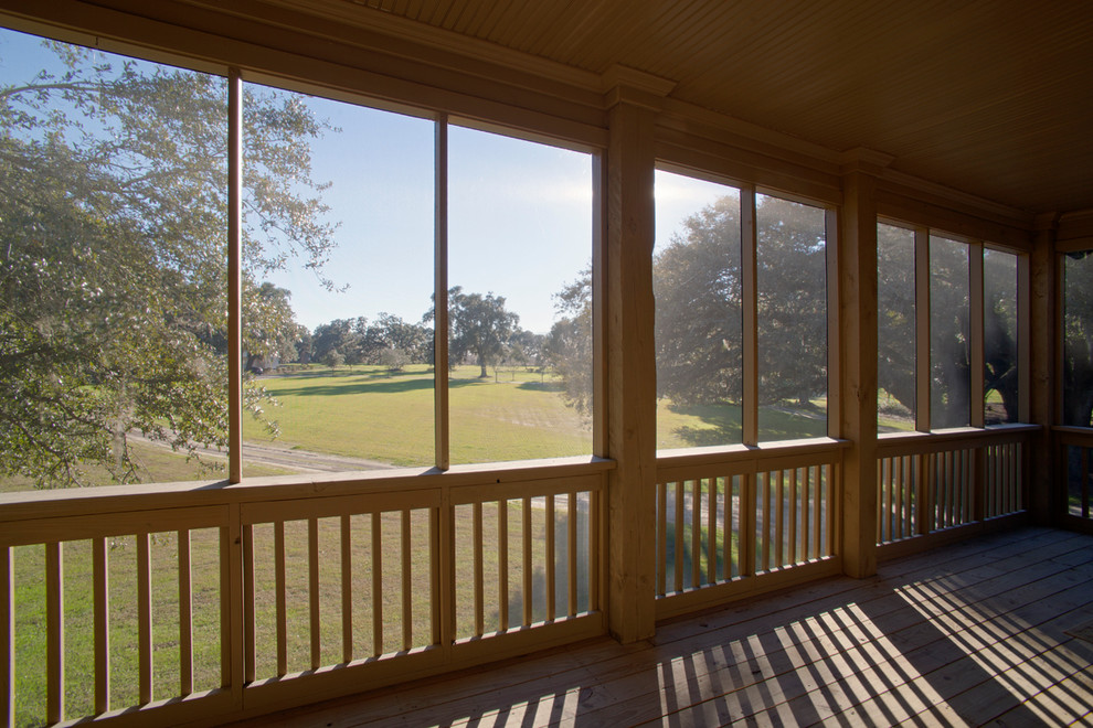 Cette photo montre un grand porche d'entrée de maison arrière nature avec une moustiquaire, une terrasse en bois et un auvent.