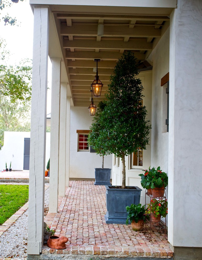 Design ideas for an expansive classic front veranda in Houston with feature lighting, brick paving and a roof extension.