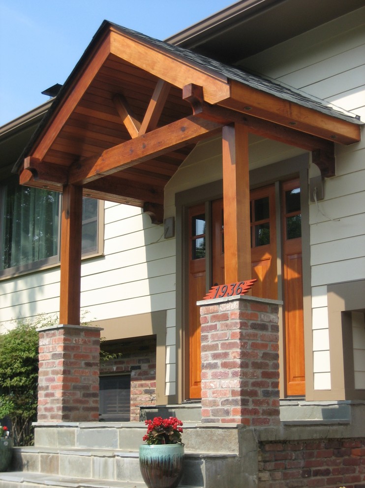Inspiration för en mellanstor amerikansk veranda framför huset, med kakelplattor och en pergola