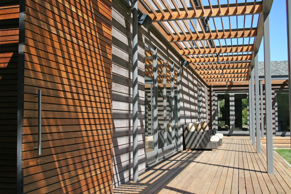 Diseño de terraza moderna de tamaño medio en patio trasero con pérgola