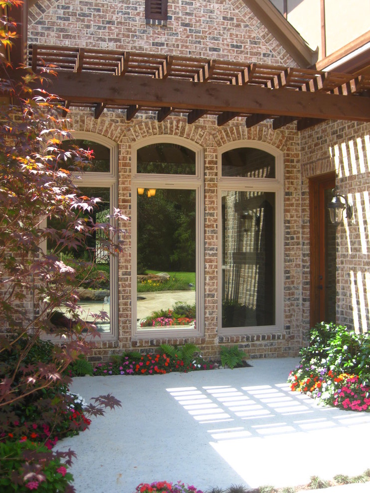 Exemple d'un très grand porche d'entrée de maison arrière chic avec une dalle de béton et une pergola.