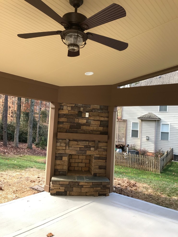 Traditional back veranda in Charlotte with a fireplace and brick paving.