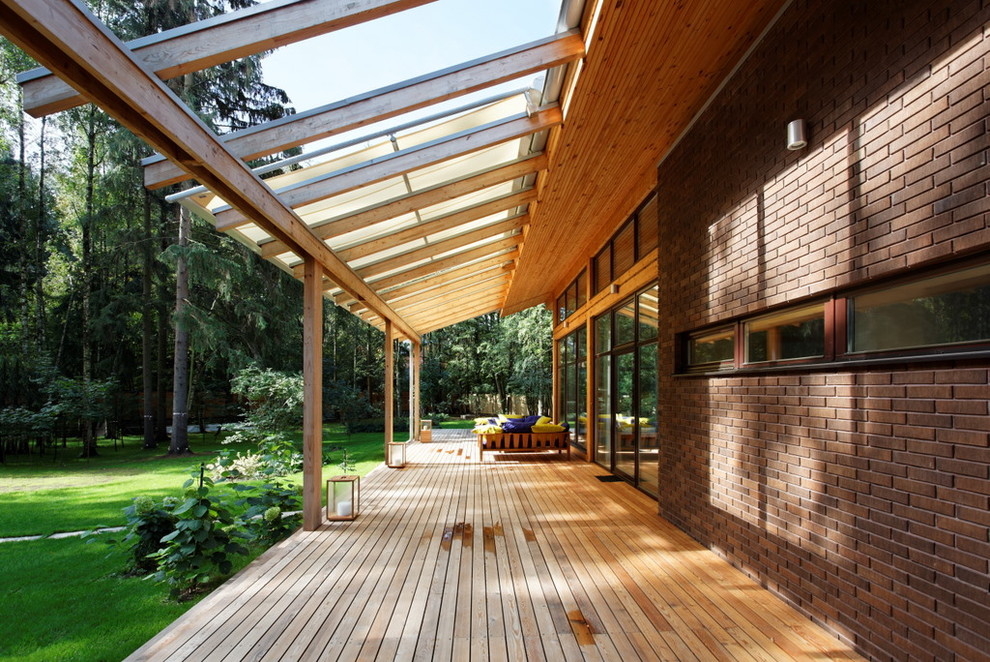 Inspiration pour un porche d'entrée de maison design avec une terrasse en bois et une extension de toiture.