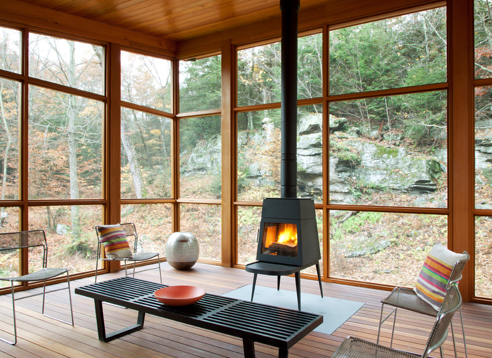 Cette photo montre un porche d'entrée de maison tendance avec un foyer extérieur, une terrasse en bois et une extension de toiture.