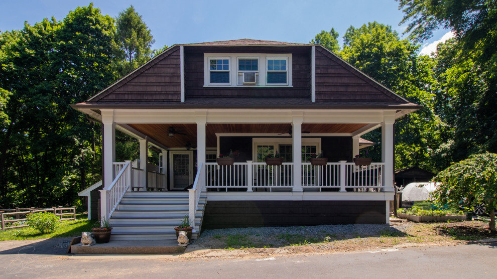 Immagine di un grande portico stile americano davanti casa con pedane e un tetto a sbalzo