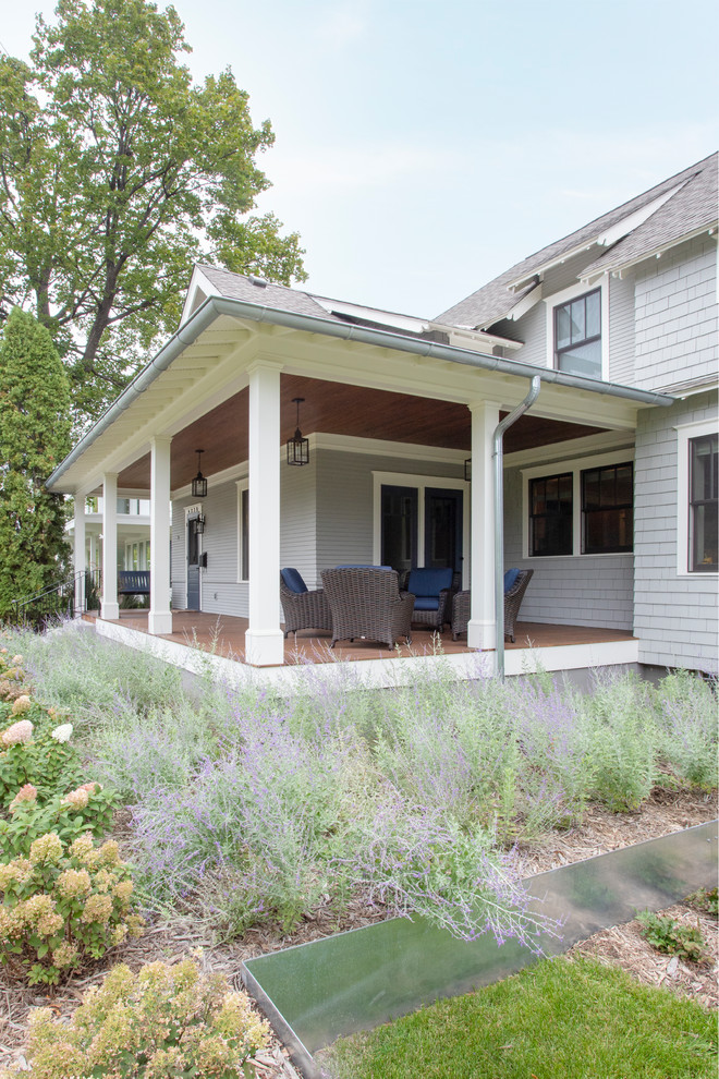 Inspiration pour un grand porche d'entrée de maison avant traditionnel avec une terrasse en bois et une extension de toiture.