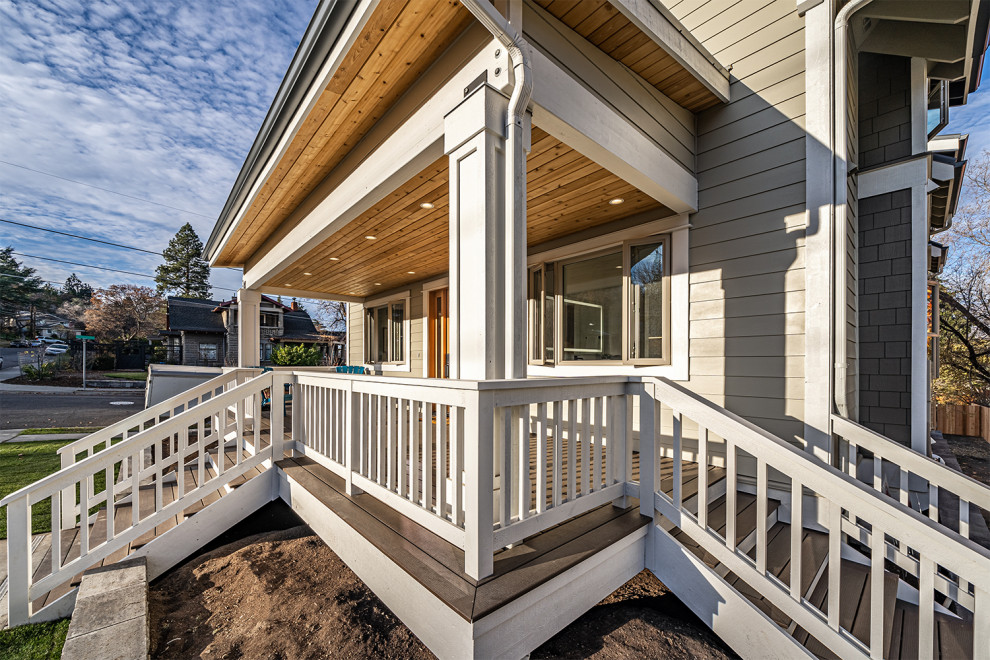 Cette image montre un grand porche d'entrée de maison avant design avec des colonnes, une terrasse en bois et une extension de toiture.