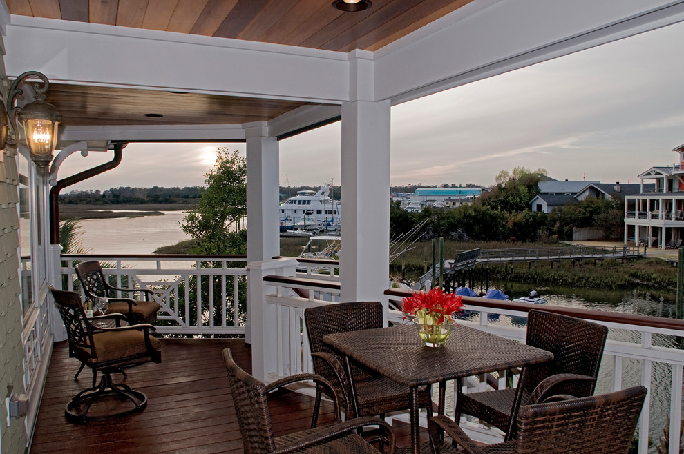 This is an example of a large coastal wood railing front porch design in Wilmington with decking and a roof extension.
