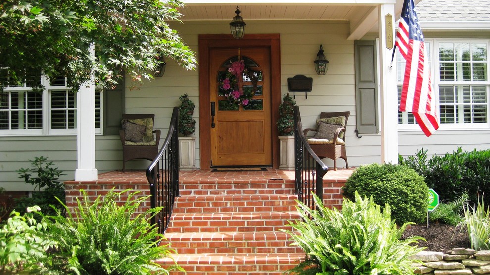 Cette photo montre un porche d'entrée de maison avant chic avec des pavés en brique et une extension de toiture.