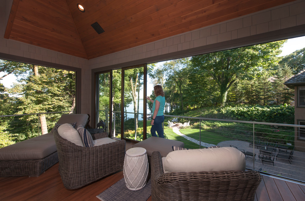 Cette photo montre un grand porche d'entrée de maison arrière bord de mer avec une moustiquaire, une terrasse en bois et une extension de toiture.