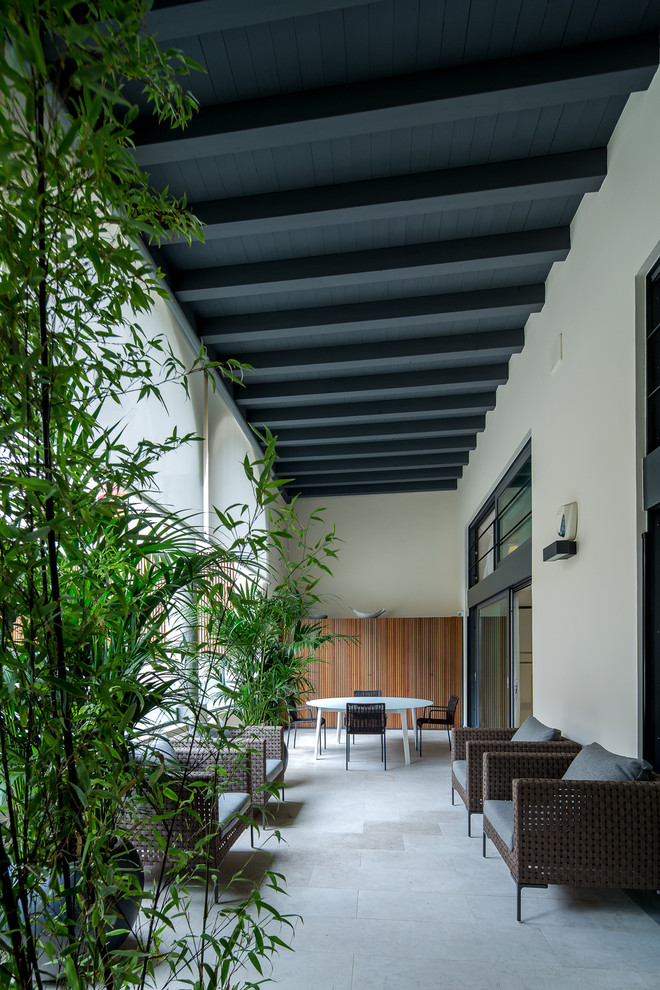 Idee per un grande portico design davanti casa con un giardino in vaso, pavimentazioni in pietra naturale e un tetto a sbalzo