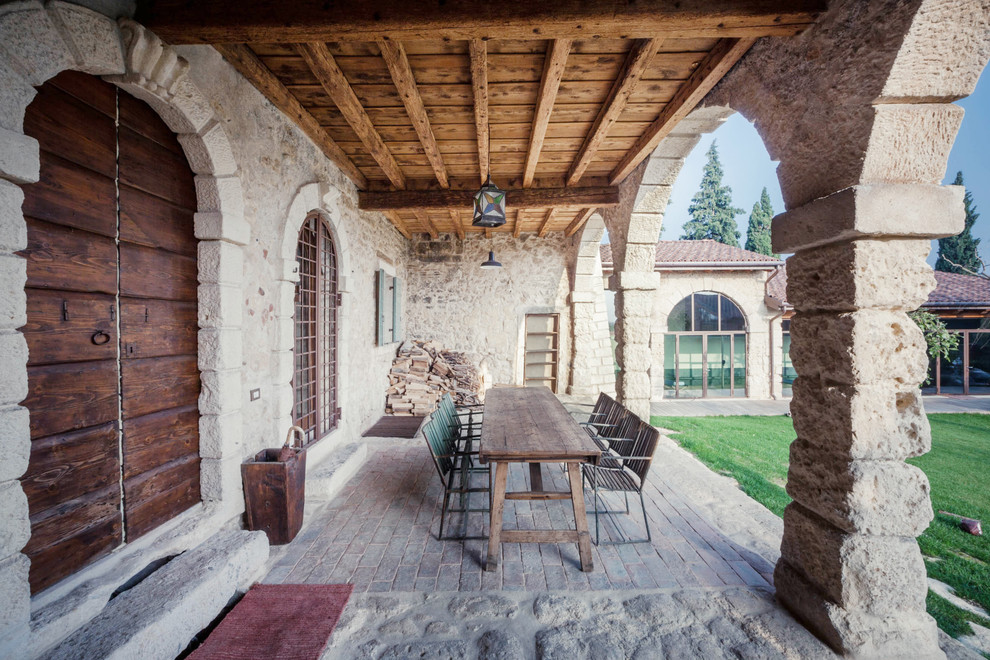Modelo de terraza de estilo de casa de campo grande en patio delantero con adoquines de piedra natural