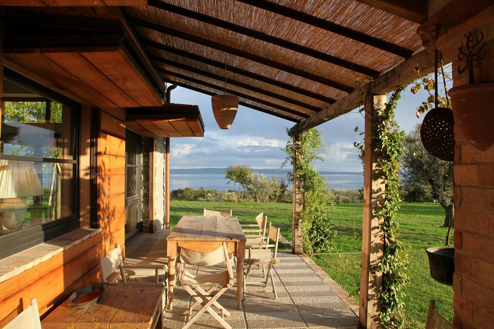 Foto de terraza de estilo de casa de campo de tamaño medio en patio trasero con adoquines de piedra natural