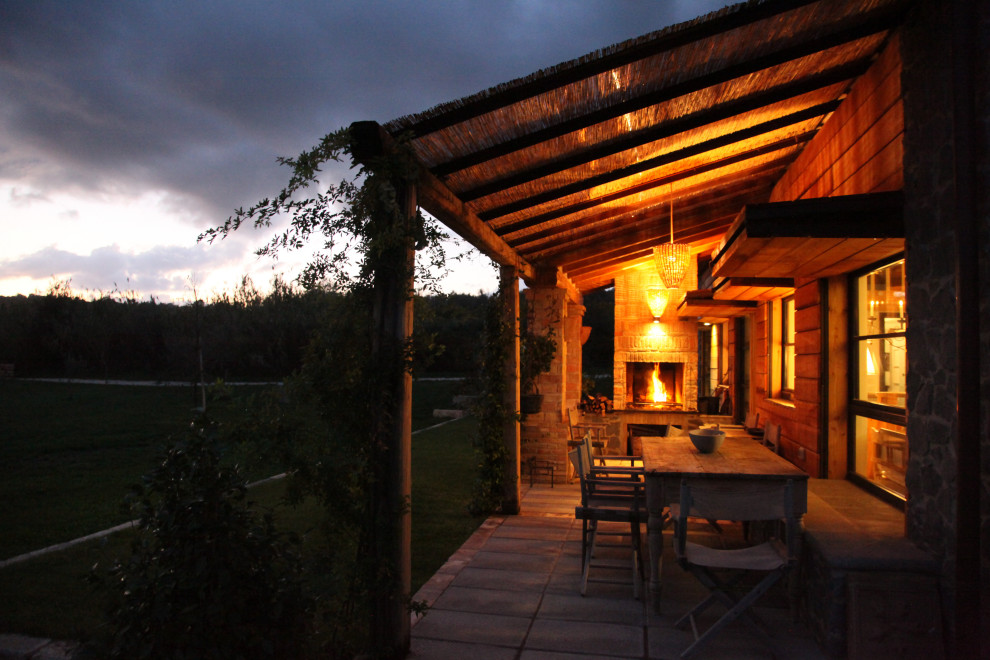 Diseño de terraza de estilo de casa de campo pequeña en patio delantero y anexo de casas con chimenea y adoquines de ladrillo