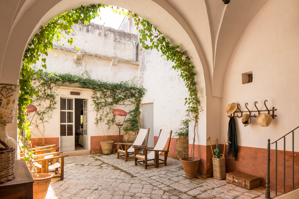 Imagen de porche cerrado mediterráneo extra grande en patio delantero con adoquines de piedra natural