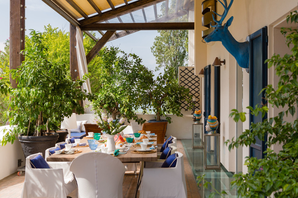 Diseño de terraza mediterránea con jardín de macetas y toldo