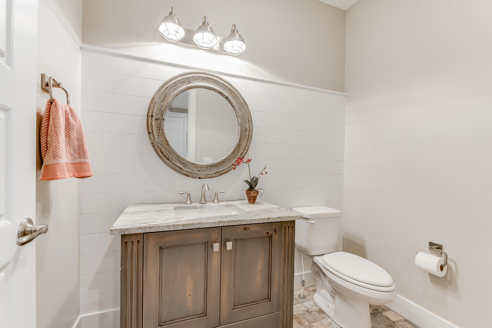 Klassisk inredning av ett litet toalett, med luckor med infälld panel, en toalettstol med separat cisternkåpa, flerfärgad kakel, porslinskakel, beige väggar, klinkergolv i porslin, ett undermonterad handfat, granitbänkskiva och skåp i slitet trä