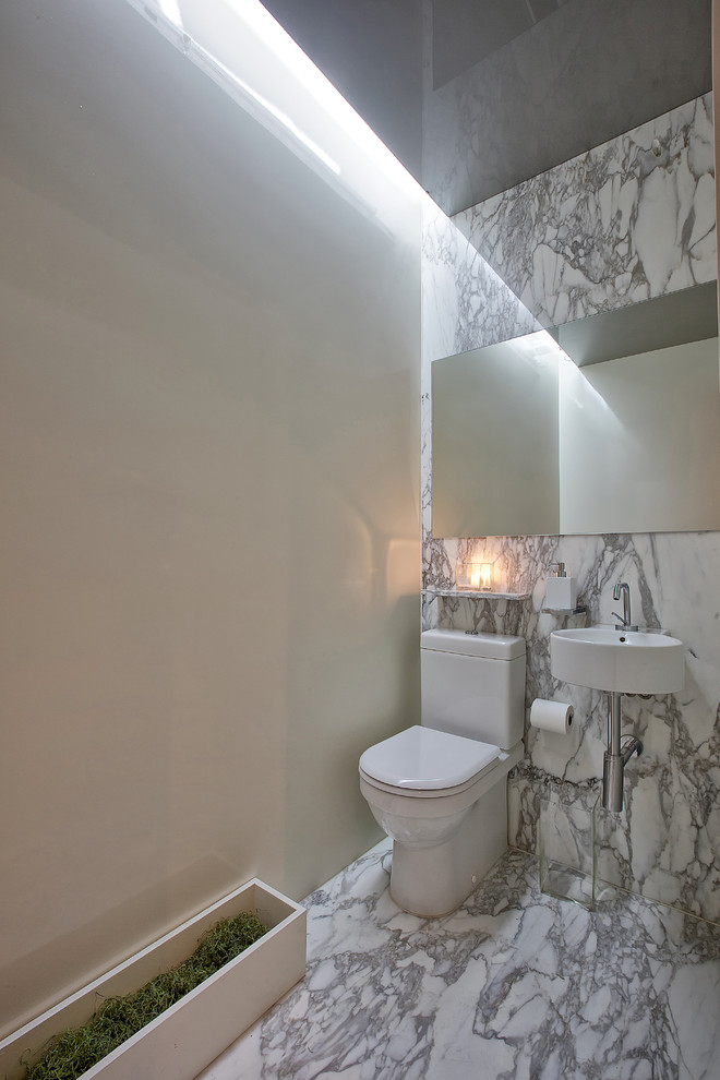 На фото: туалет в современном стиле с подвесной раковиной, раздельным унитазом, белой плиткой, плиткой из листового камня и бежевыми стенами с