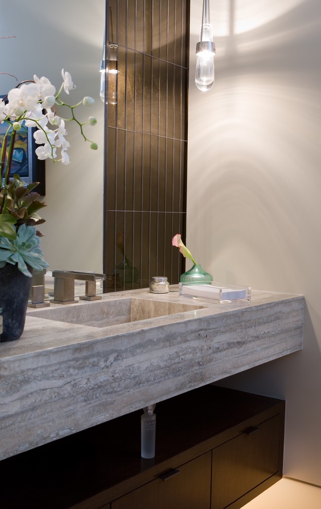 Modelo de aseo minimalista con paredes grises, lavabo integrado, encimera de piedra caliza y suelo beige