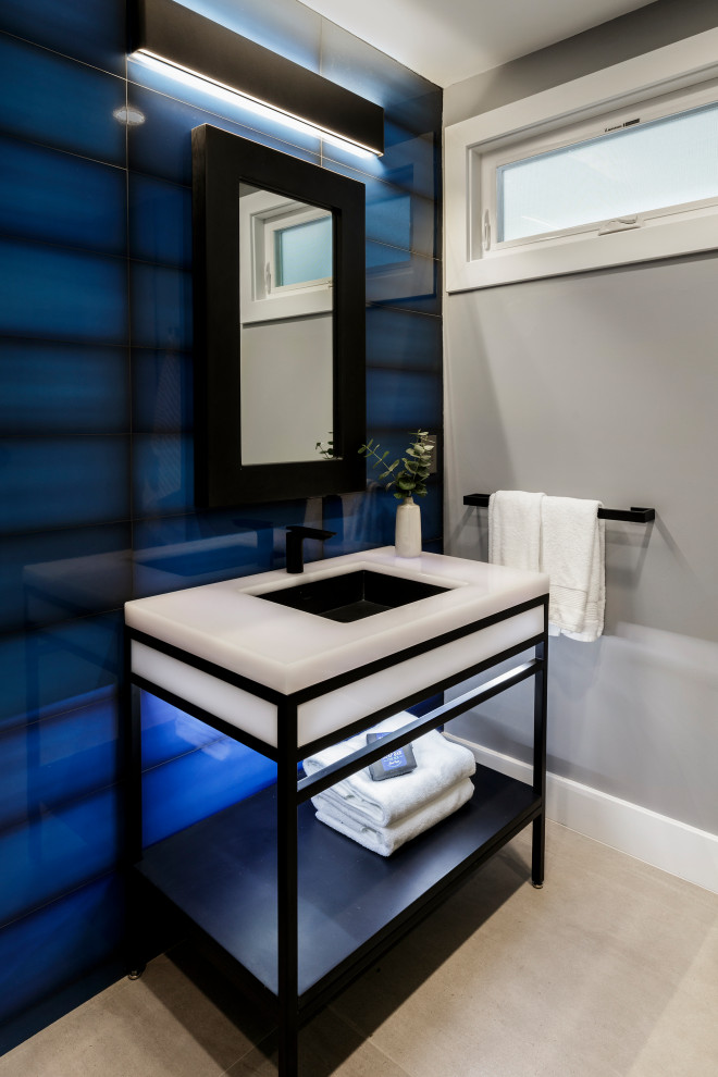 На фото: туалет в современном стиле с синей плиткой, серыми стенами, врезной раковиной, серым полом и напольной тумбой с