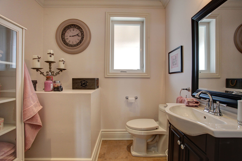 Aménagement d'un WC et toilettes classique en bois foncé de taille moyenne avec un lavabo intégré, WC à poser, un carrelage beige, un mur gris et un sol en carrelage de porcelaine.